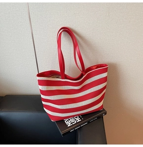 Detailaufnahme einer rot-weiß gestreiften Strick-Tote-Bag mit roten Lederriemen auf Sofa