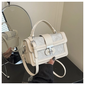 Close-up of cream square handbag showing vintage jacquard texture and silver twist lock
