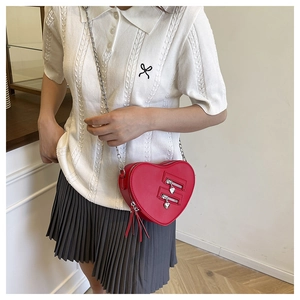 Detail of red heart-shaped crossbody bag with dual silver zippers and chain strap