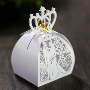 Macro shot of laser-cut white wedding favor box with crown top and Mr & Mrs design