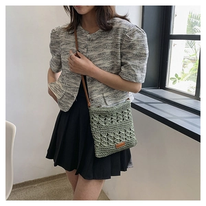 Detail of forest green woven crossbody bag featuring intricate hollow weave textures