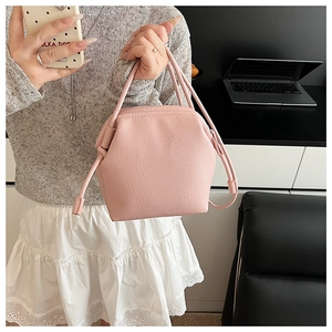 Pink dumpling bag with lychee texture being carried in a modern indoor lifestyle scene
