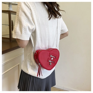 Detail of red heart-shaped crossbody bag with silver chain and leather tassels