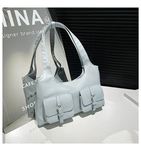 Détail du sac bandoulière en cuir bleu clair avec deux poches avant à rabat bouclé