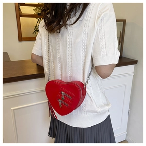 Detailed view of red heart-shaped PU leather crossbody bag with chain strap on a model