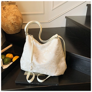 Detail of white jacquard tote bag with floral texture and drawstring bead accents