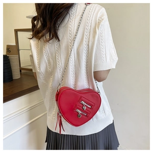 Rear view of model wearing a stylish red heart-shaped crossbody bag with silver chain