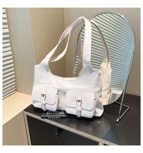 Détail du sac blanc avec deux poches frontales ornées de boucles métalliques élégantes