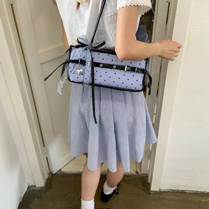 Close-up of light blue polka dot bag featuring large mesh bow and heart pendant