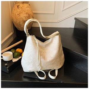 Detail of white jacquard hobo bag with floral texture on dark wooden steps