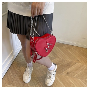 Detail of red heart-shaped crossbody bag with silver zippers and elegant chain strap