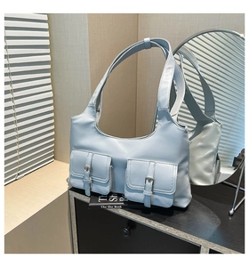 Détail d'un sac hobo bleu clair avec deux poches à rabat et boucles en métal argenté