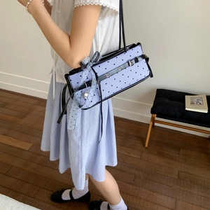 Detail of light blue baguette bag featuring heart patterns and decorative polka dot ribbon