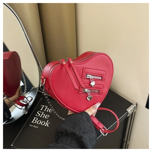 Close-up of bright red heart-shaped bag with dual zippers and silver heart charms