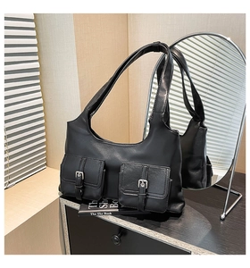 Détail d'un sac porté épaule noir en similicuir avec poches pratiques et boucles argentées