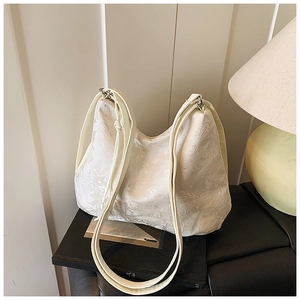 Detailed view of cream hobo bag with embossed floral patterns and thin shoulder straps