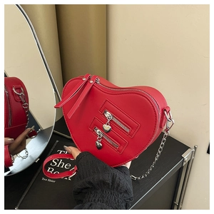 Detail of red heart-shaped crossbody bag with silver chains and dual zipper accents