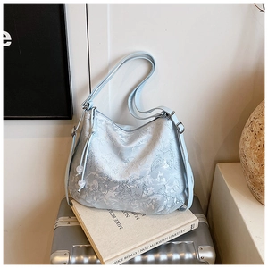 Close-up of light blue embroidered floral shoulder bag with drawstring bead detail