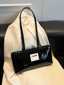 Glossy black patent leather baguette bag with white logo patch on white blazer