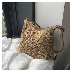 Close-up of woven hollow texture and brown faux leather strap on khaki straw crossbody bag