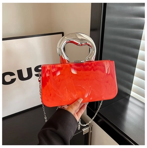 Detail of red marble acrylic crossbody bag with silver sculptural handle and metal chain