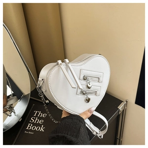 Detail of white heart-shaped crossbody bag with silver chain and dual zippers