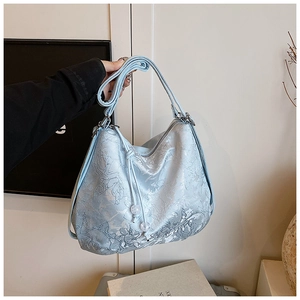 Detail of light blue jacquard hobo bag with floral relief texture and beaded drawstring