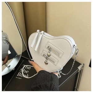 Detail of white heart-shaped crossbody bag with dual zippers and silver chain strap