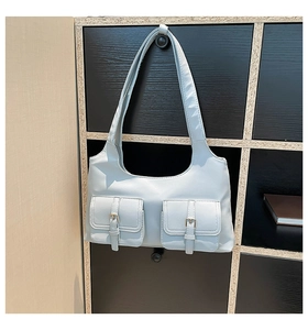 Détail d'un sac à bandoulière en cuir bleu clair avec deux poches à rabat et boucles métal