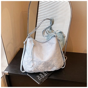 Detail of light blue embroidered floral tote bag with tassel drawstring near a mirror