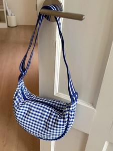 Blue and white checkered crescent canvas shoulder bag with adjustable striped strap