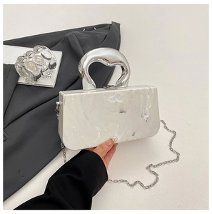 Detail of marble pattern acrylic handbag with chunky silver heart-shaped metal handle