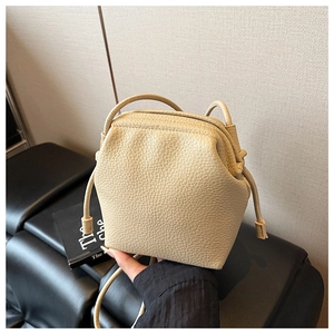 Détail du mini sac bandoulière en cuir beige grainé avec un design trapèze plissé unique