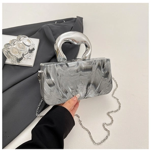 Detail of marble texture clutch bag with polished silver handle and chain strap
