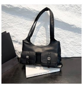 Détail d'un sac à bandoulière noir mat avec deux poches et des boucles argentées