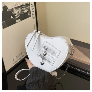 Detail view of heart-shaped crossbody bag with dual zippers and silver chain strap