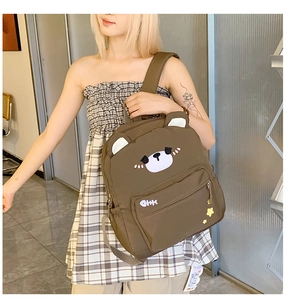 Detail of cute brown bear canvas backpack with star and fish bone patches worn by a model