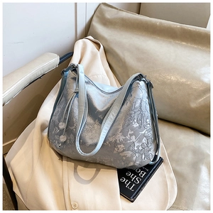 Detail of light blue embroidered tote bag with delicate floral patterns and shoulder straps