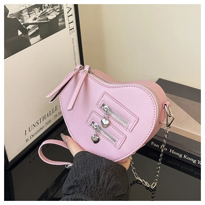 Detail of pink heart-shaped crossbody bag with decorative silver zippers and chain strap