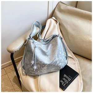 Close-up of light blue embroidered shoulder bag with floral textures and beaded drawstring