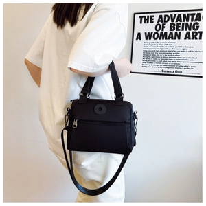 Detail of black nylon crossbody bag with rubber logo and wide shoulder strap shown on model