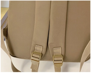 Close-up of durable fabric shoulder straps and adjustable buckles on a brown canvas backpack