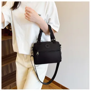 Detail of black fabric crossbody bag with circular logo and adjustable wide shoulder strap