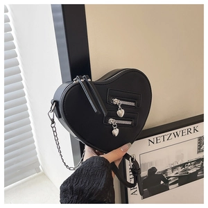 Detail of a black heart-shaped crossbody bag with silver zippers and chain strap