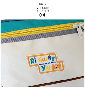 Detailed close-up of vintage style embroidery and bright yellow zipper on makeup bag