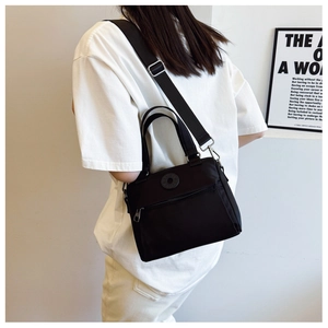 Detail of a versatile black nylon crossbody bag with adjustable wide fabric shoulder strap