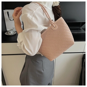 Detail van roze gevlochten emmertas met schouderband gedragen door een model binnen