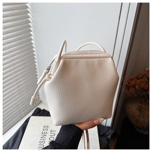Gros plan sur la texture cuir litchi blanc crème et le design hexagonal du sac bandoulière