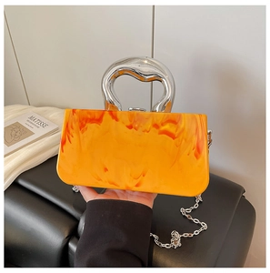 Detail of orange marble acrylic purse with a sculptural silver metal handle and chain