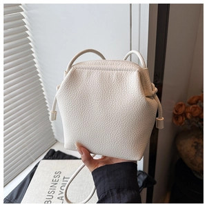 Gros plan d'un sac seau en cuir blanc avec motif litchi et design géométrique épuré